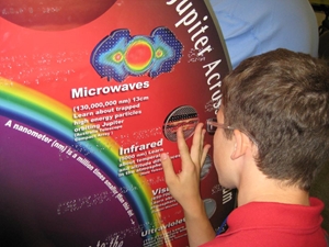 A student touches the Jupiter image on the Solar System Radio Explorer Kiosk (SSREK)