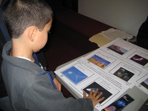 A museum visitor explores tactile images from Here, There and Everywhere NASA exhibit