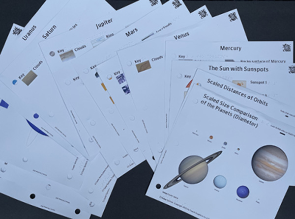 This photo shows all 16 tactile images from Touch the Solar System,arranged at different angles and on top of each other. Only one colorfultactile image on the top is completely visible; 
a size comparison of the planets.